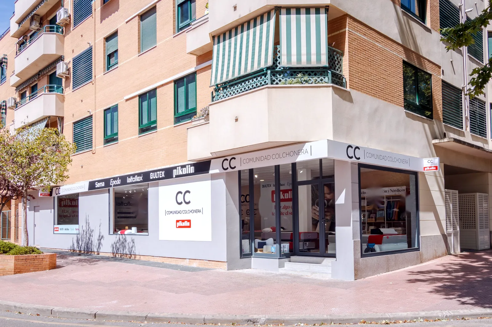 Fachada en esquina de la tienda Comunidad Colchonera en la calle José María Pereda, 3, Alcalá de Henares, con los rótulos de Pikolin, Bultex, Lattoflex, Epeda y Sema