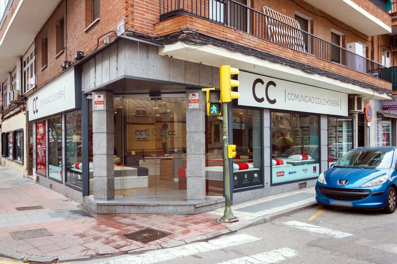 Fachada de la tienda Comunidad Colchonera de Getafe, en la esquina de la Avenida Juan de la Cierva, con el rótulo y los escaparates de colchones