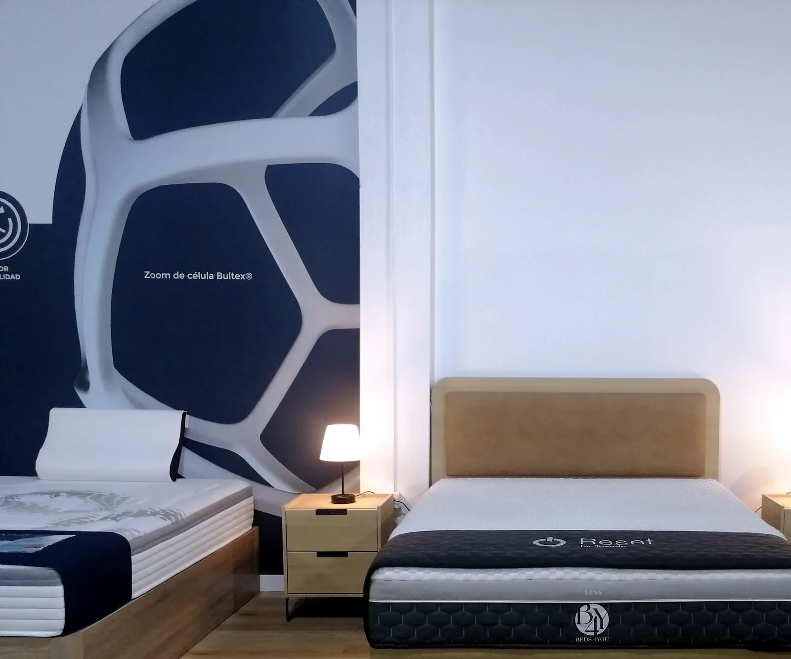 Cama con cabecero y mesitas a juego junto a colchones y canapés en la tienda Comunidad Colchonera de Torrejón de Ardoz
